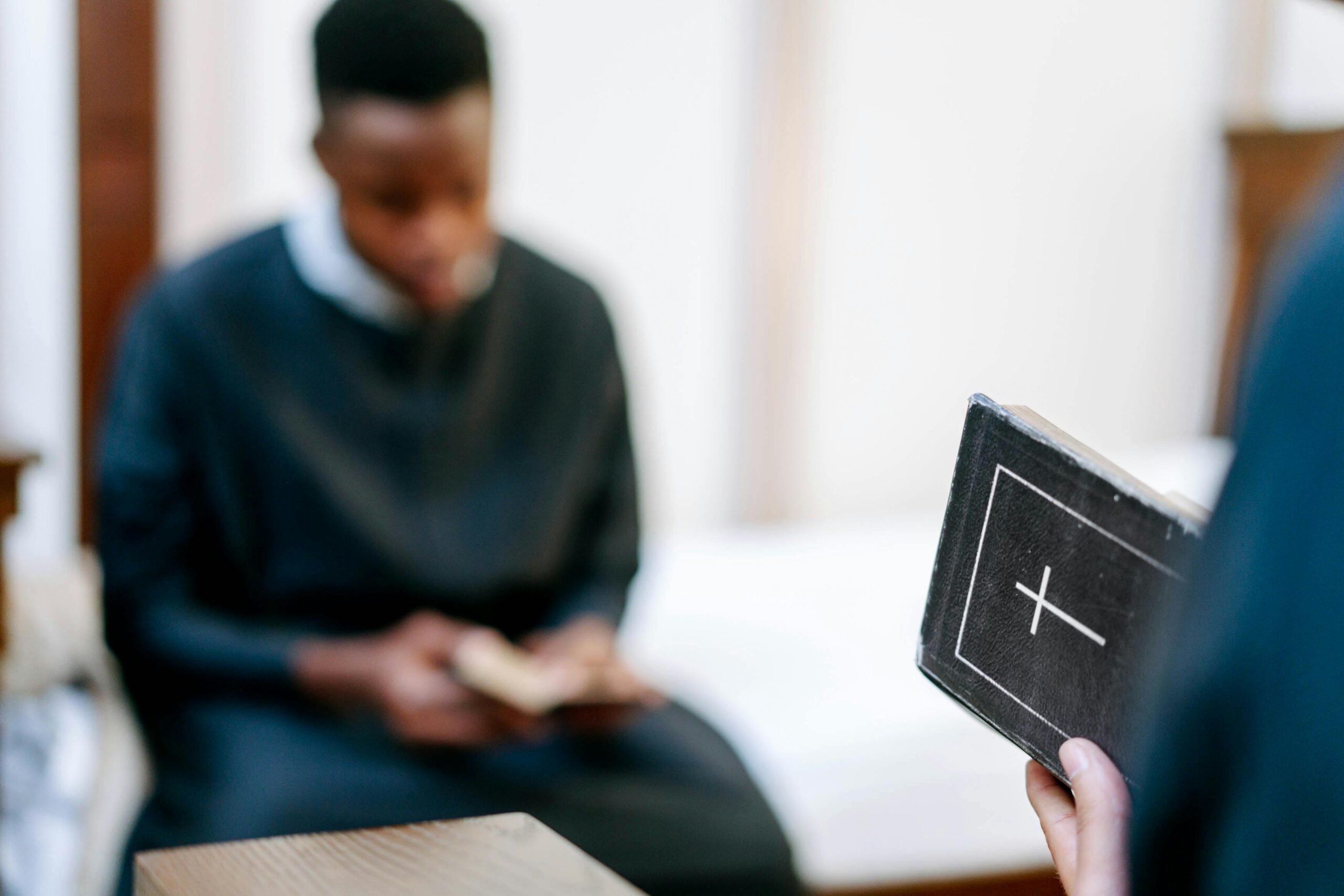 A person in religious attire reads a Bible indoors, focusing on faith and reflection.